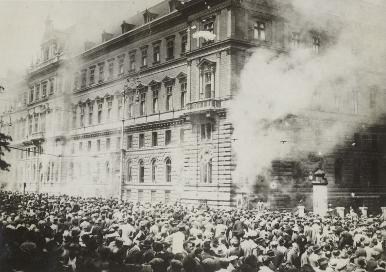 Blick auf den brennenden Justizpalast, davor eine große Menschenmenge